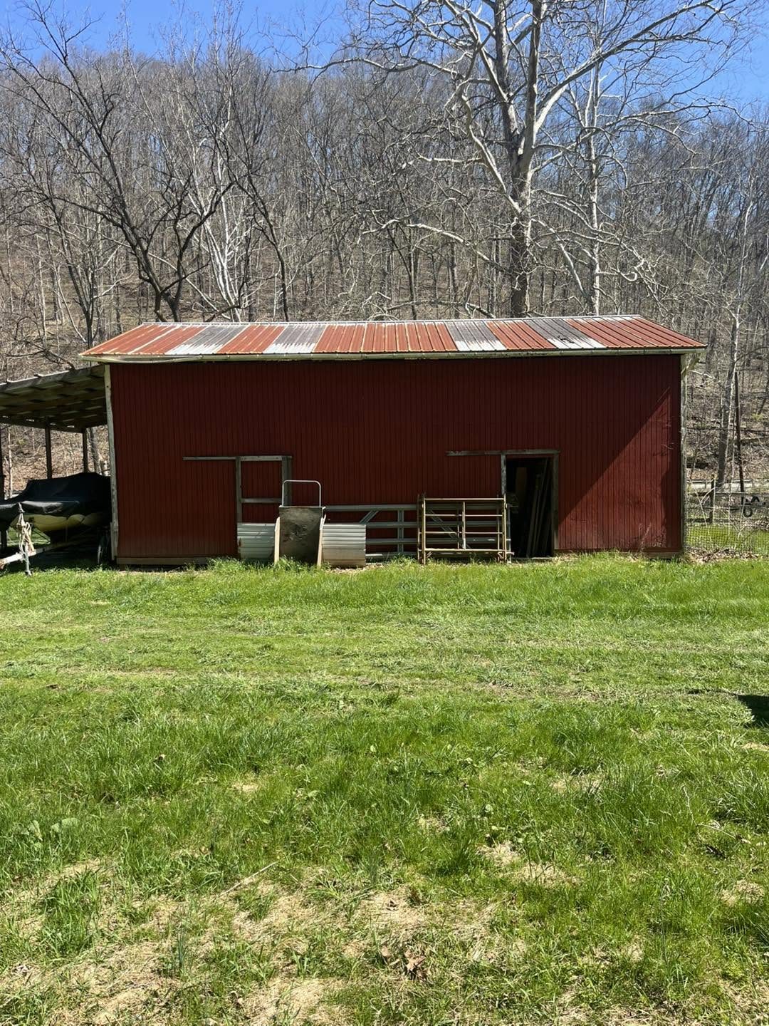 Red barn with a rusted metal roof before coating