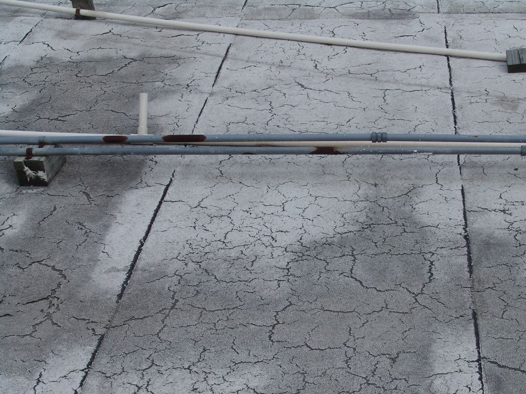 A worn flat roof membrane cracked across its whole surface